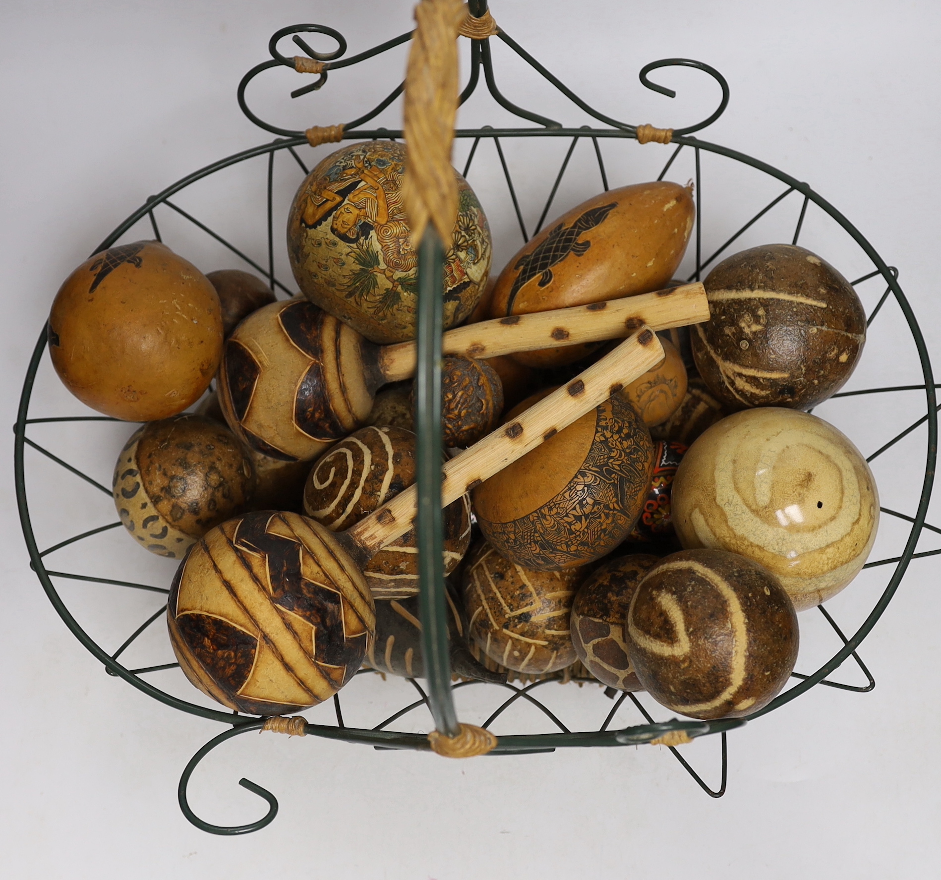 A wirework basket, containing assorted decorated gourds, nuts from Indonesia etc.
